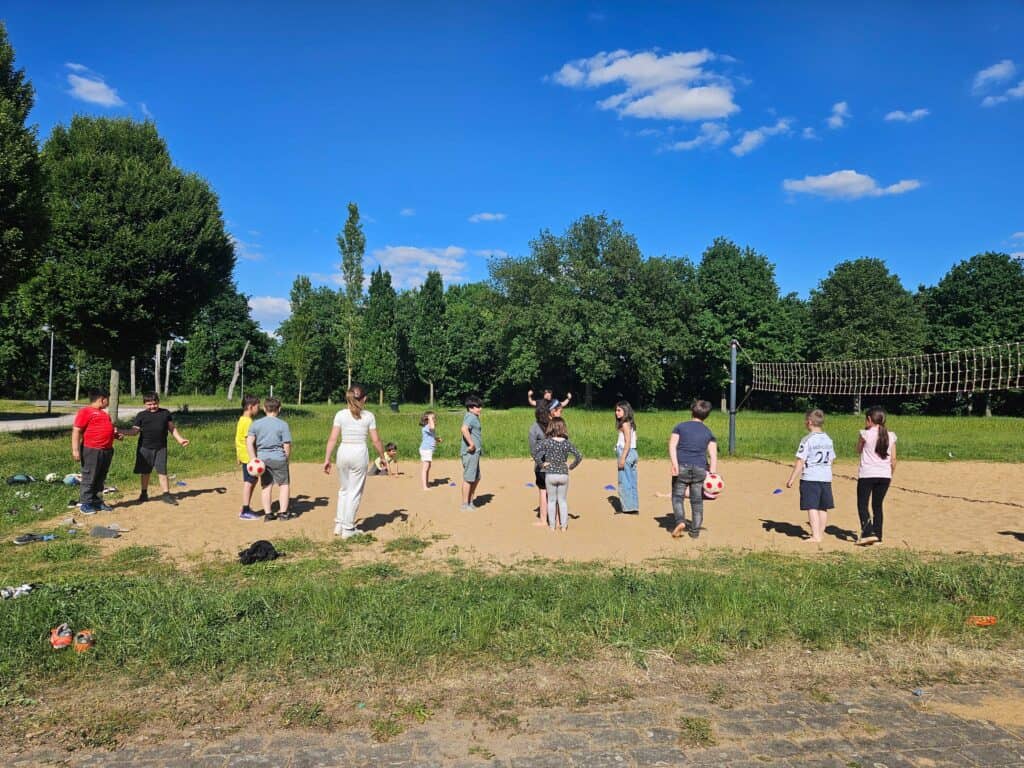 Gruppen von Menschen beim Yoga im Freien auf einer Wiese bei sonnigem Himmel.