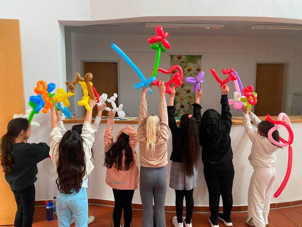 Kinder mit Ballonfiguren bei einer Feier im Innenraum.